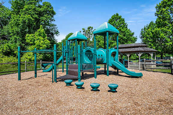 A playground with a green slide and toy chest.