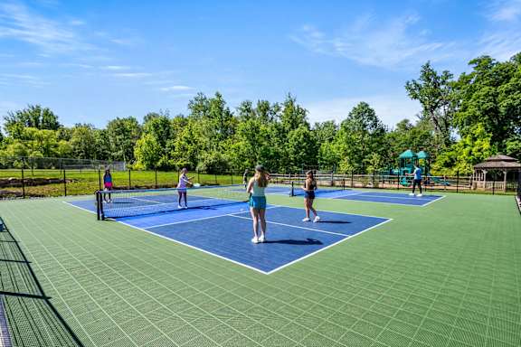 A group of people playing tennis on a blue court.