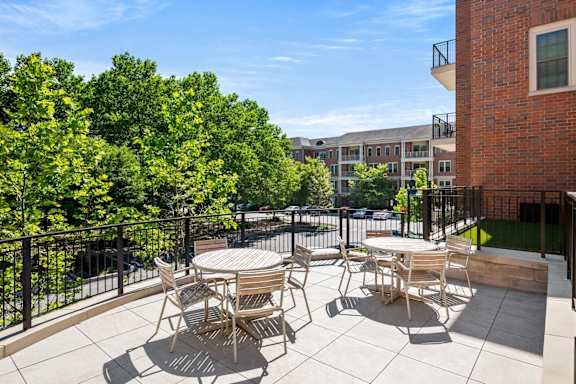 A patio with a table and chairs overlooks a tree-filled courtyard.