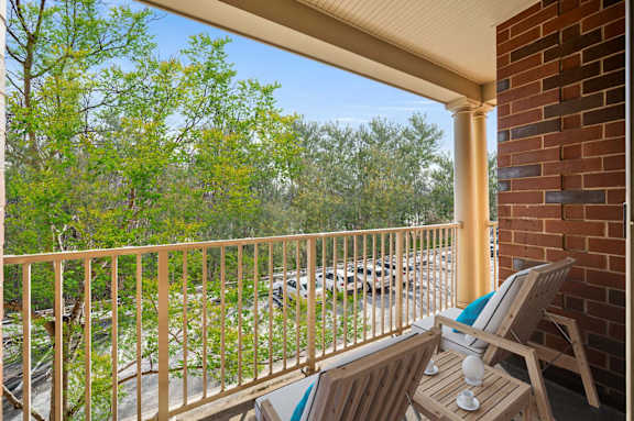 A balcony with a chair and a table with a cup on it.
