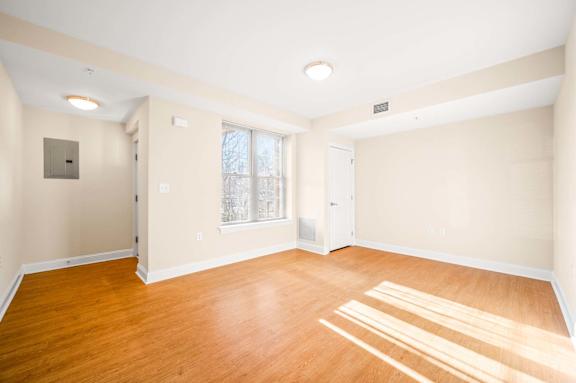 A room with wooden flooring and a window with white blinds.