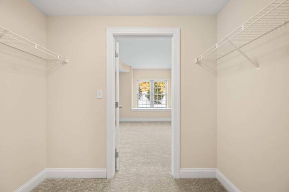 A white door is open to a hallway with a carpeted floor.