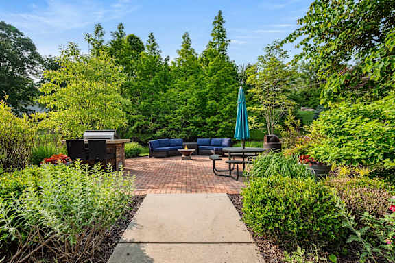 A backyard with a blue umbrella and a brick patio.