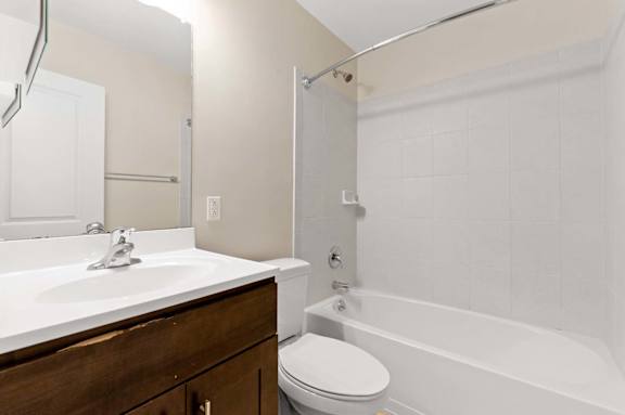 A white sink with a wooden cabinet and a white toilet in a bathroom.
