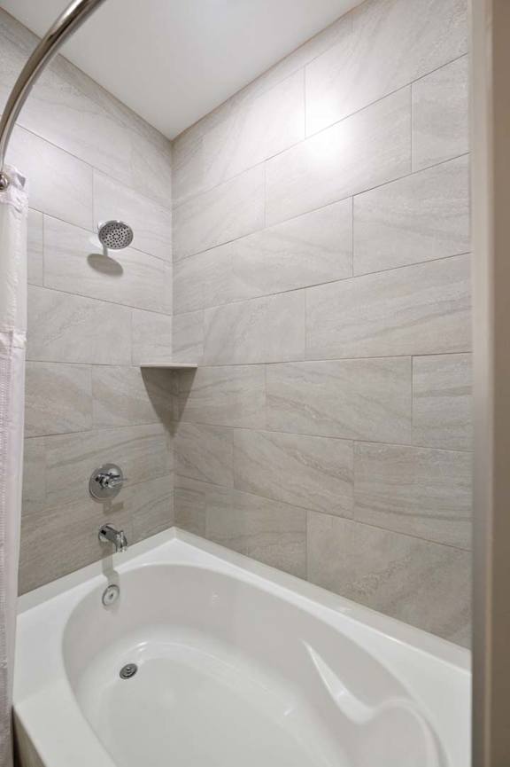 A white bathtub with a shower head and faucet.