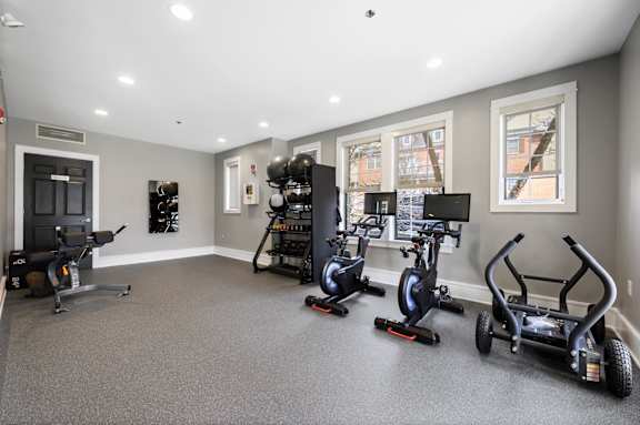 A room with a grey floor and a row of exercise bikes.