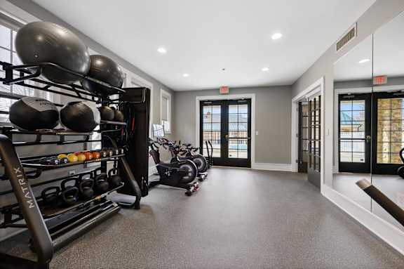A spacious room with a row of kettles on a rack and a row of exercise bikes.