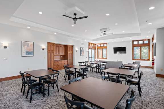 A room with tables and chairs and a ceiling fan.