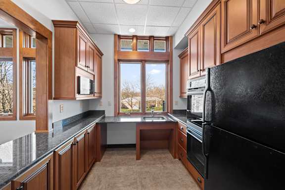 A kitchen with brown cabinets and a black refrigerator.
