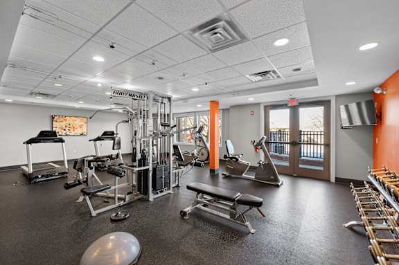 A gym with a variety of equipment including a treadmill, weights, and a bench press.