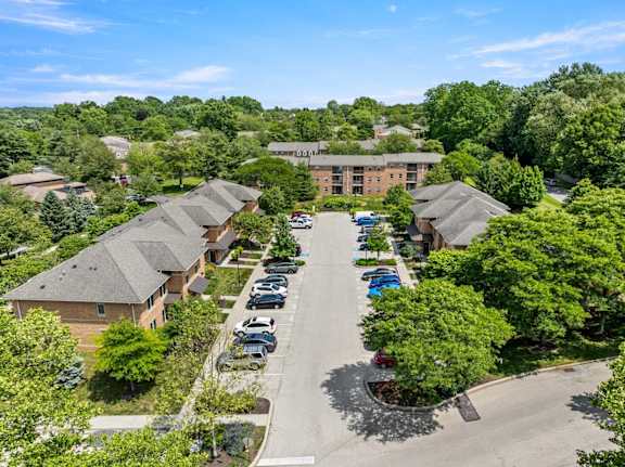 A parking lot is surrounded by trees and a building.