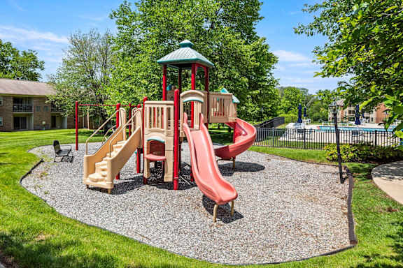 A playground with a red slide and a green roofed structure.