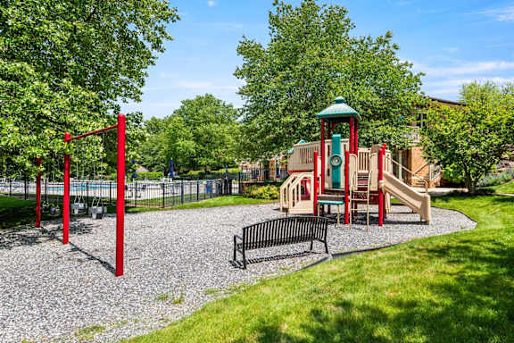 A playground with a red swing set and a green and red play structure.