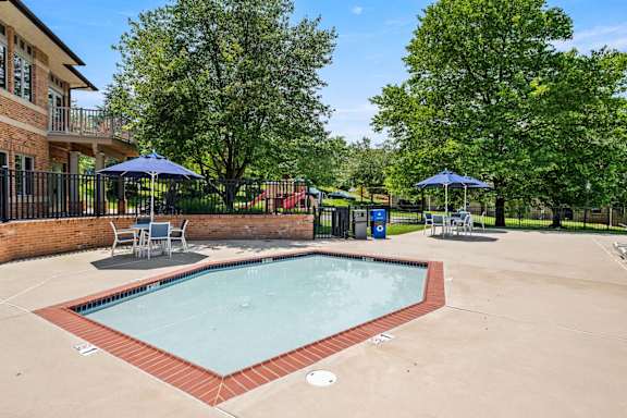 A small pool surrounded by a brick wall and trees.