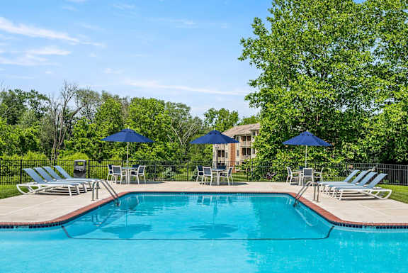 A swimming pool surrounded by lawn chairs and umbrellas.