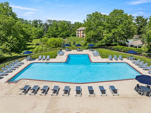 A large swimming pool surrounded by lounge chairs and umbrellas.