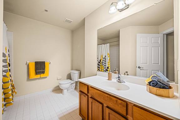 A bathroom with a toilet, sink, and mirror.