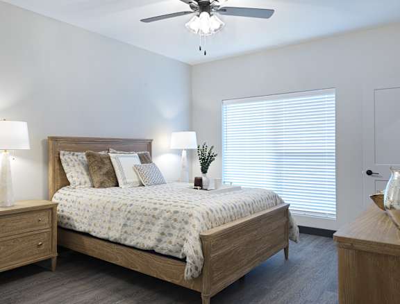 A bedroom with a bed, nightstand, and a ceiling fan.