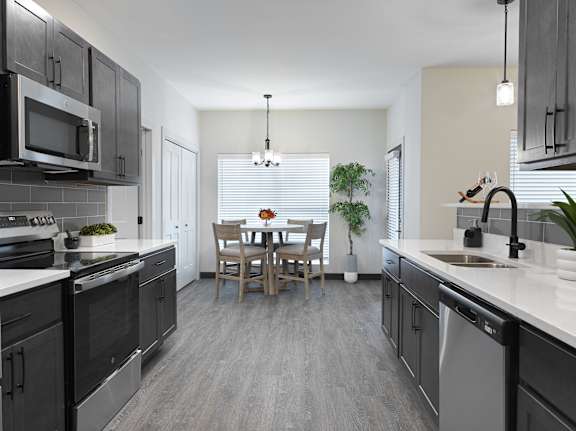 A modern kitchen with dark cabinets and a dining table set for two.