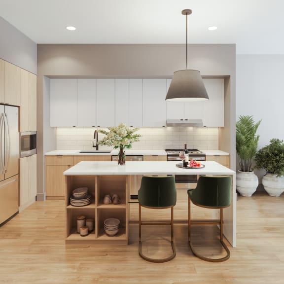 a kitchen with white cabinets and a white island with green chairs at Bemiston Place Apartments, Missouri