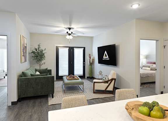 A living room with a green couch, a coffee table, and a television mounted on the wall.