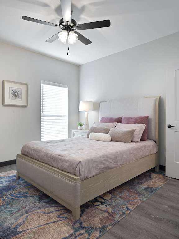A bedroom with a bed, a ceiling fan, and a rug.