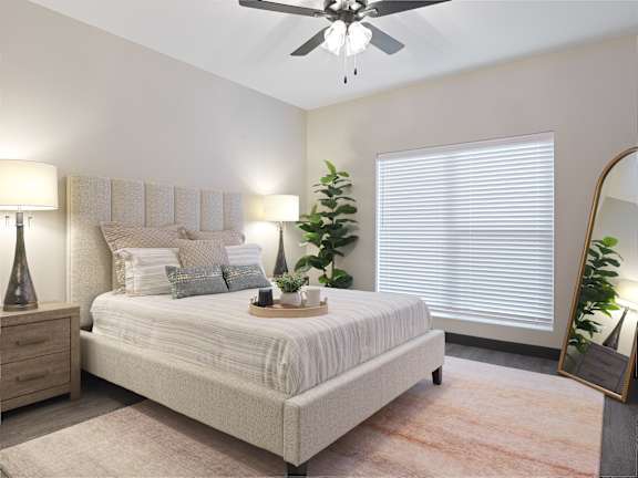 A bedroom with a bed, a ceiling fan, and a mirror.
