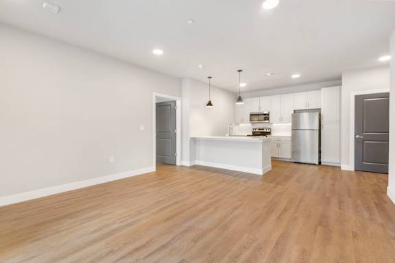 A kitchen with white cabinets and a wooden floor.