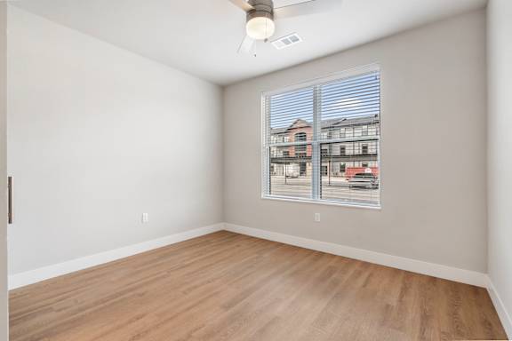 A room with a window showing a view of a building outside.