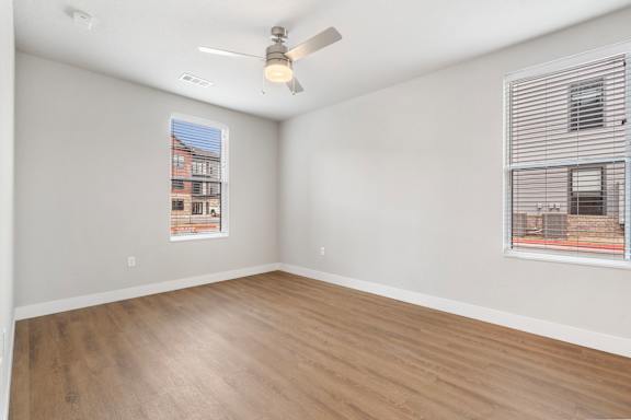 A room with a ceiling fan and a window with a view of a building.