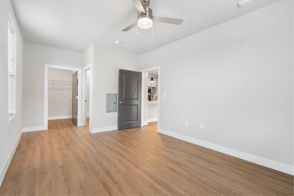 A room with a ceiling fan and a grey refrigerator.