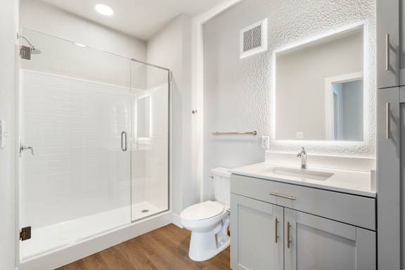 A white bathroom with a walk in shower and toilet.