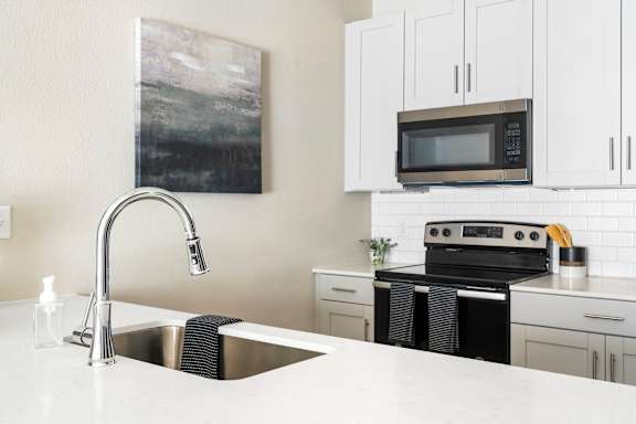 A modern kitchen with a sink, stove, and cabinets.