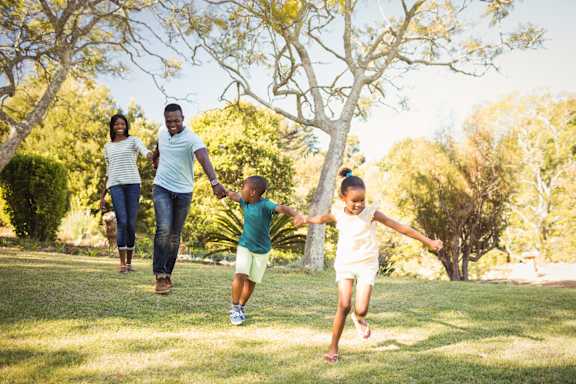 A family of four running in a park.