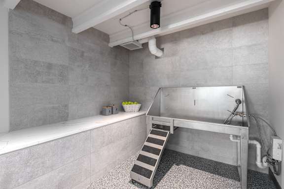 A stainless steel sink in a room with grey tiled walls.