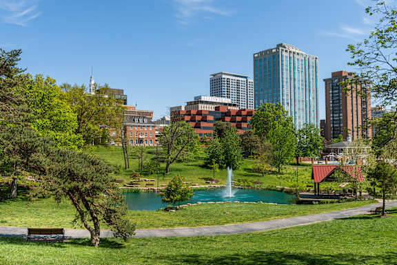 A park with a pond and a fountain in the middle of it.