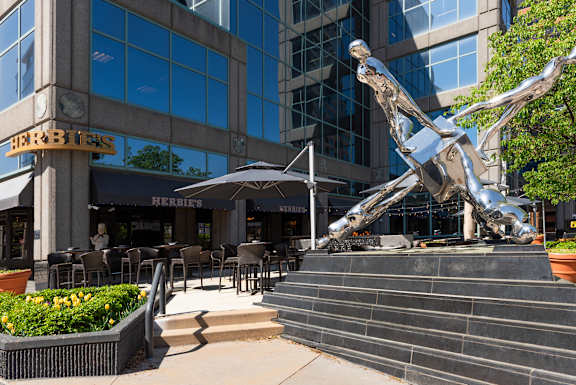 A large metal sculpture of a person is in front of a Herbies restaurant.