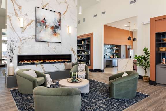 A living room with a fireplace, a painting on the wall, and a green armchair at Hawk Ridge Apartments, Lake St. Louis, Missouri 63367