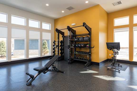 A gym with a bench, weights, and a bicycle at Hawk Ridge Apartments, Lake St. Louis, Missouri, 63367