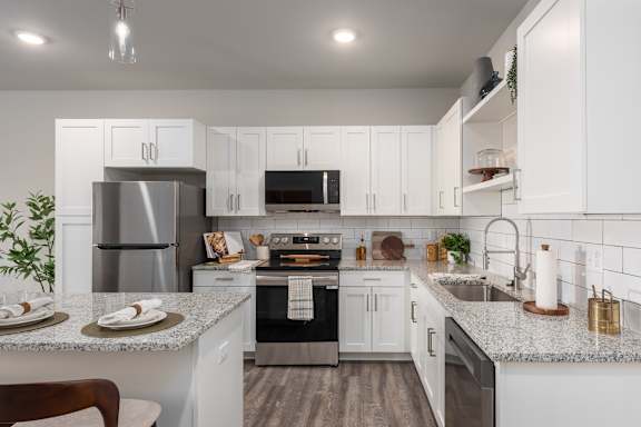 A modern kitchen with white cabinets and stainless steel appliances at Hawk Ridge Apartments, Lake St. Louis, Missouri, 63367