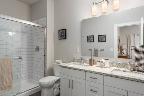 A bathroom with a toilet, sink, and mirror at Hawk Ridge Apartments, Lake St. Louis, MO, 63367