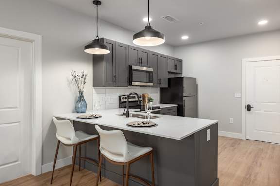 Modern kitchen with island seating and pendant lighting at Mila Apartments, Ellisville, 63011