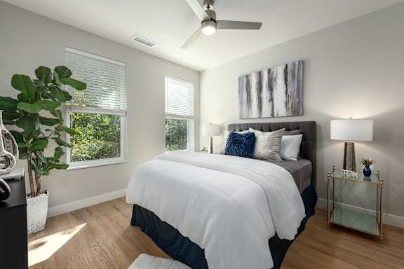 Bedroom with gray upholstered headboard and windows at Mila Apartments, Ellisville, Missouri