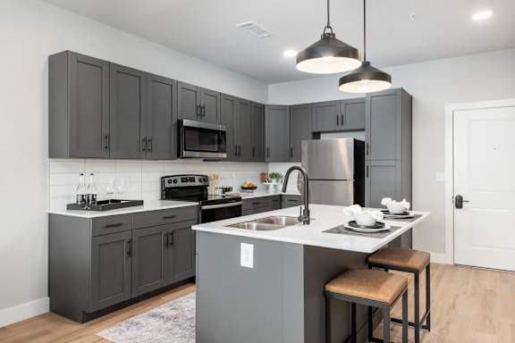 Kitchen with gray cabinetry and white countertops at Mila Apartments, Missouri, 63011