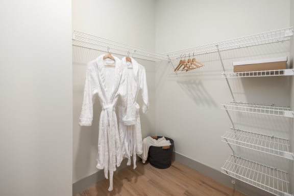 two white dresses hanging in a closet with metal shelves at Bemiston Place Apartments, Missouri