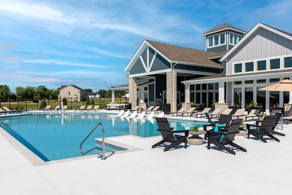A large swimming pool with lounge chairs and a building in the background.