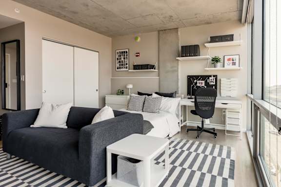 A modern living room with a grey couch, white coffee table, and a black and white striped rug. at One Foundry Way Apartments, Missouri