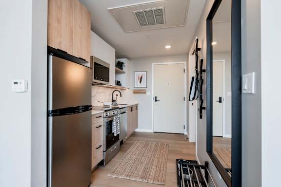 A modern kitchen with a stainless steel refrigerator and wooden cabinets. at One Foundry Way Apartments, St Louis, Missouri
