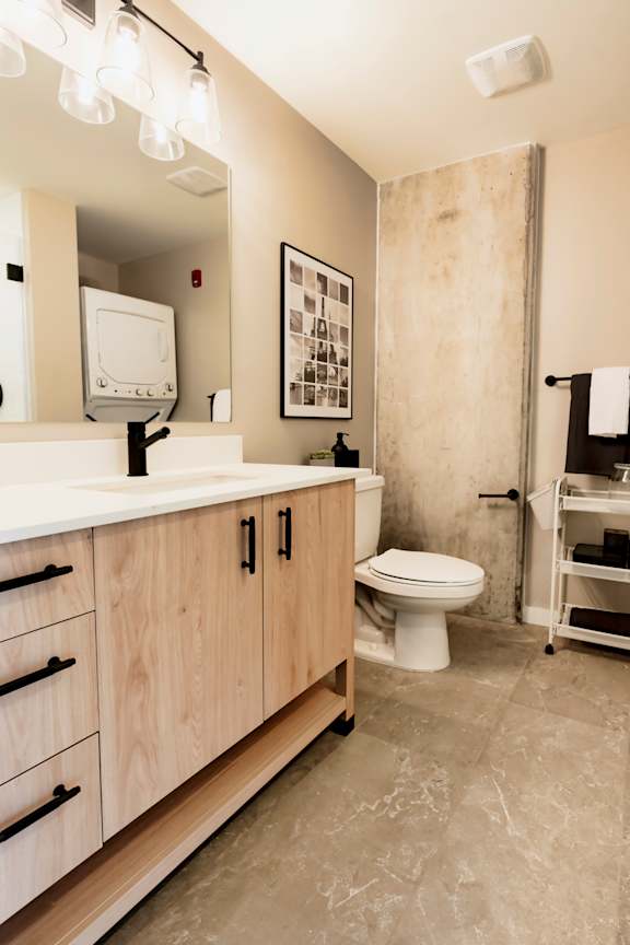 A bathroom with a toilet, sink, and a mirror. at One Foundry Way Apartments, Missouri, 63110