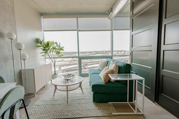 A living room with a green couch, a glass table, and a potted plant. at One Foundry Way Apartments, Missouri, 63110